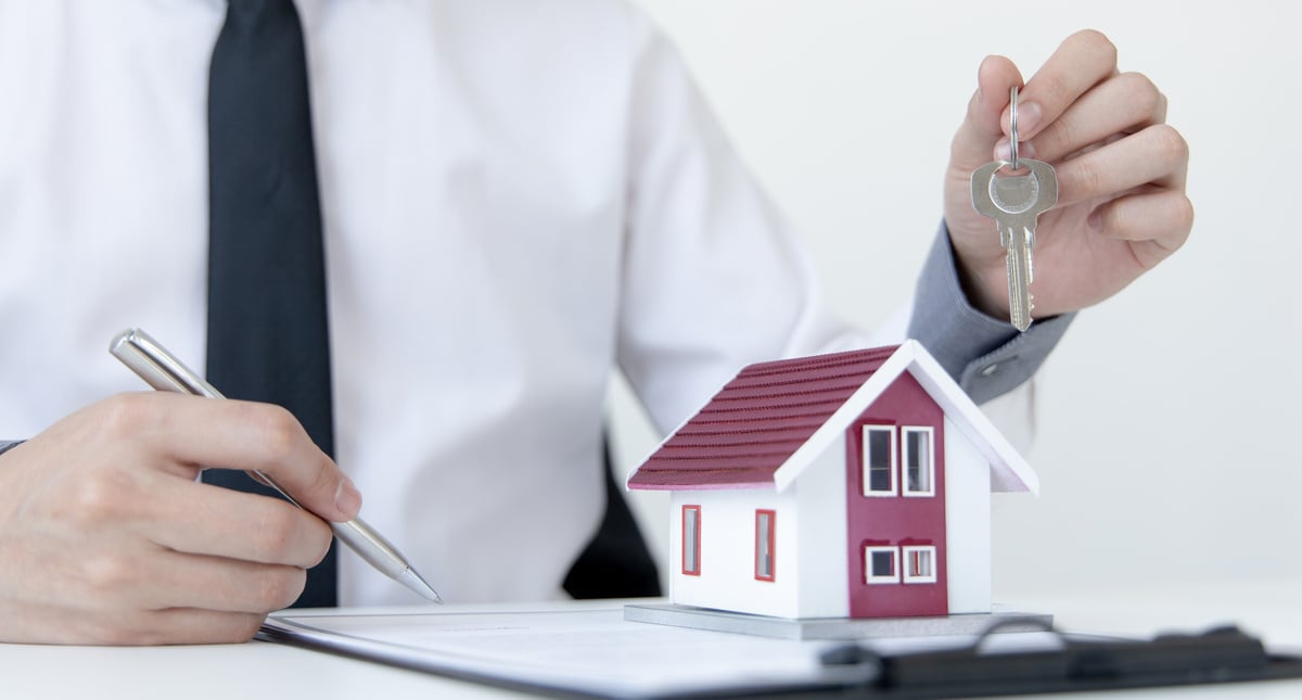 A man holding keys over a model house