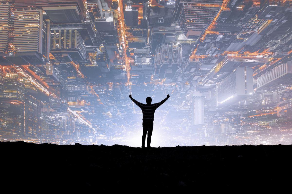 Businessman standing on top of a mountain with office buildings in front