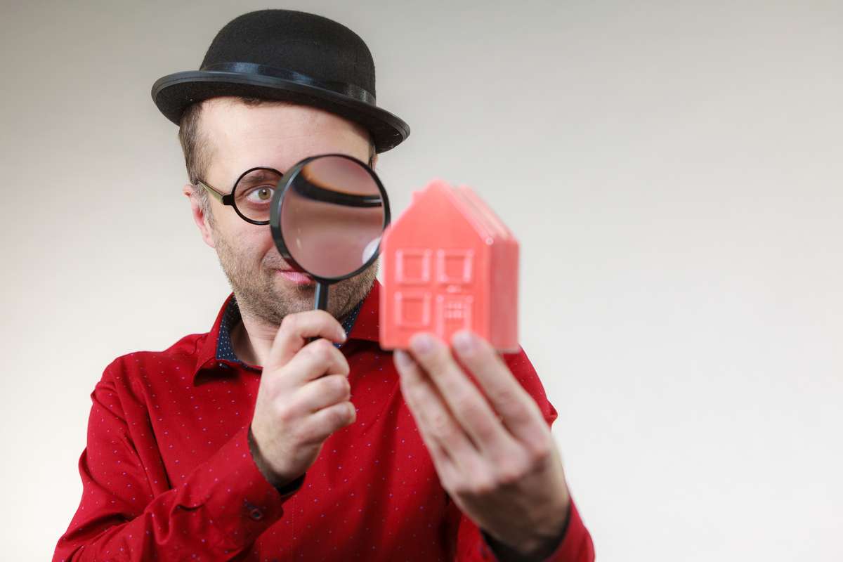 Man magnifying red house