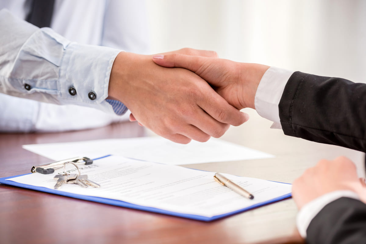 Property manger and client handshake with notice to vacate document underneath