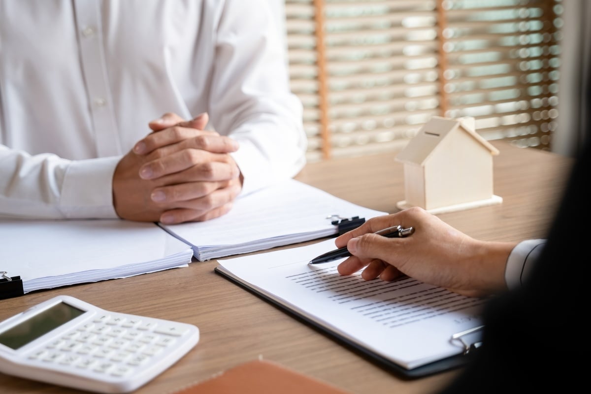 Two people meeting next to a calculator and a model home