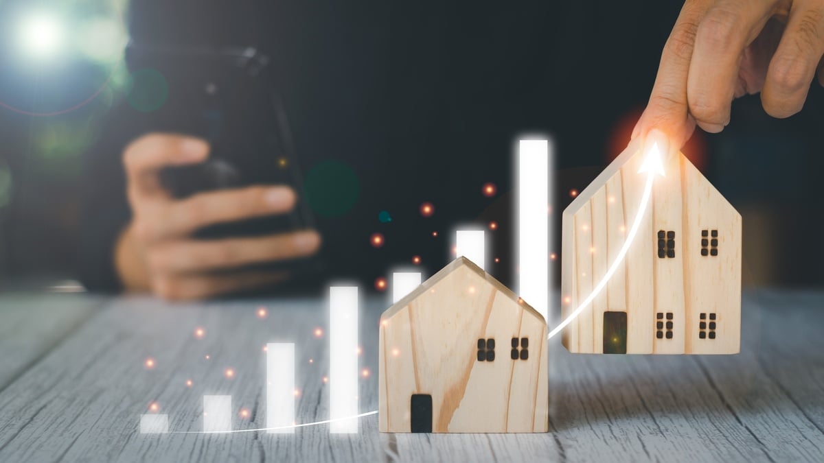 Someone holding a wooden house beside a virtual graph