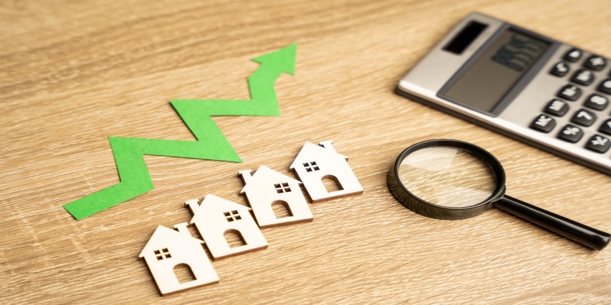 A calculator, magnifying glass, and up arrow next to small wooden houses