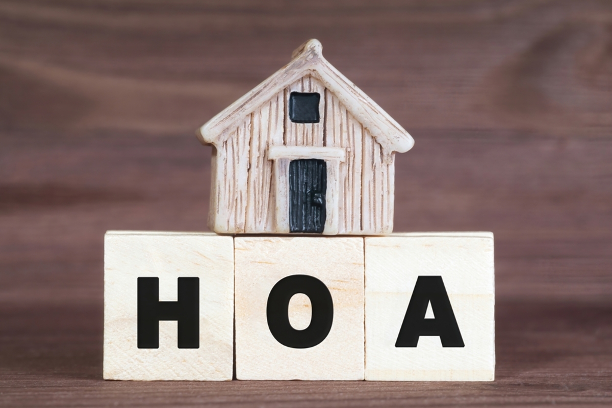 HOA abbreviation made of wooden letter blocks with a miniature house on top.