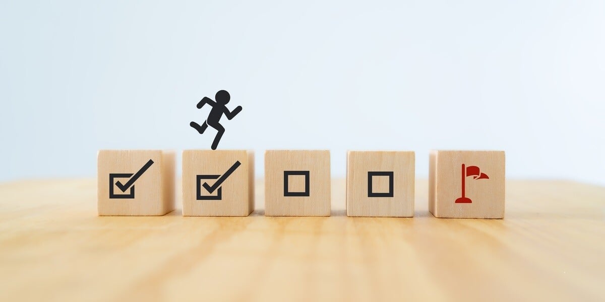 Wooden blocks showing check marks and a finish line